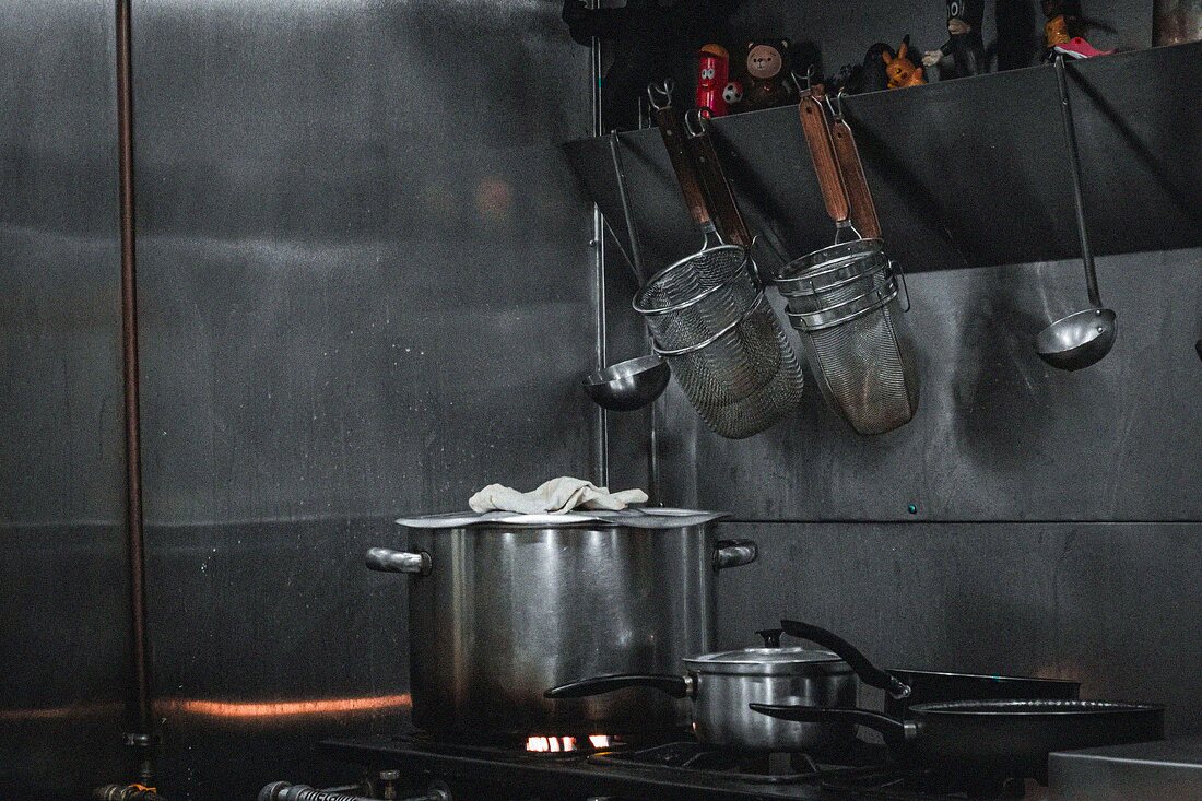 Stainless steel commercial kitchen with pots and utensils on the pass