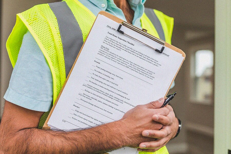Inspector holding a checklist on a clipboard during a property inspection
