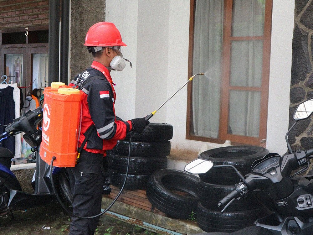 Worker in protective gear treating the exterior of a residential building